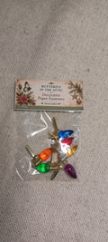 A small clear plastic bag containing decorative paper fasteners with colorful butterfly and floral designs, attached to a printed header card that reads 'Butterfly in the Attic Decorative Paper Fasteners Handmade by J.' The product is photographed on a light beige fabric background.