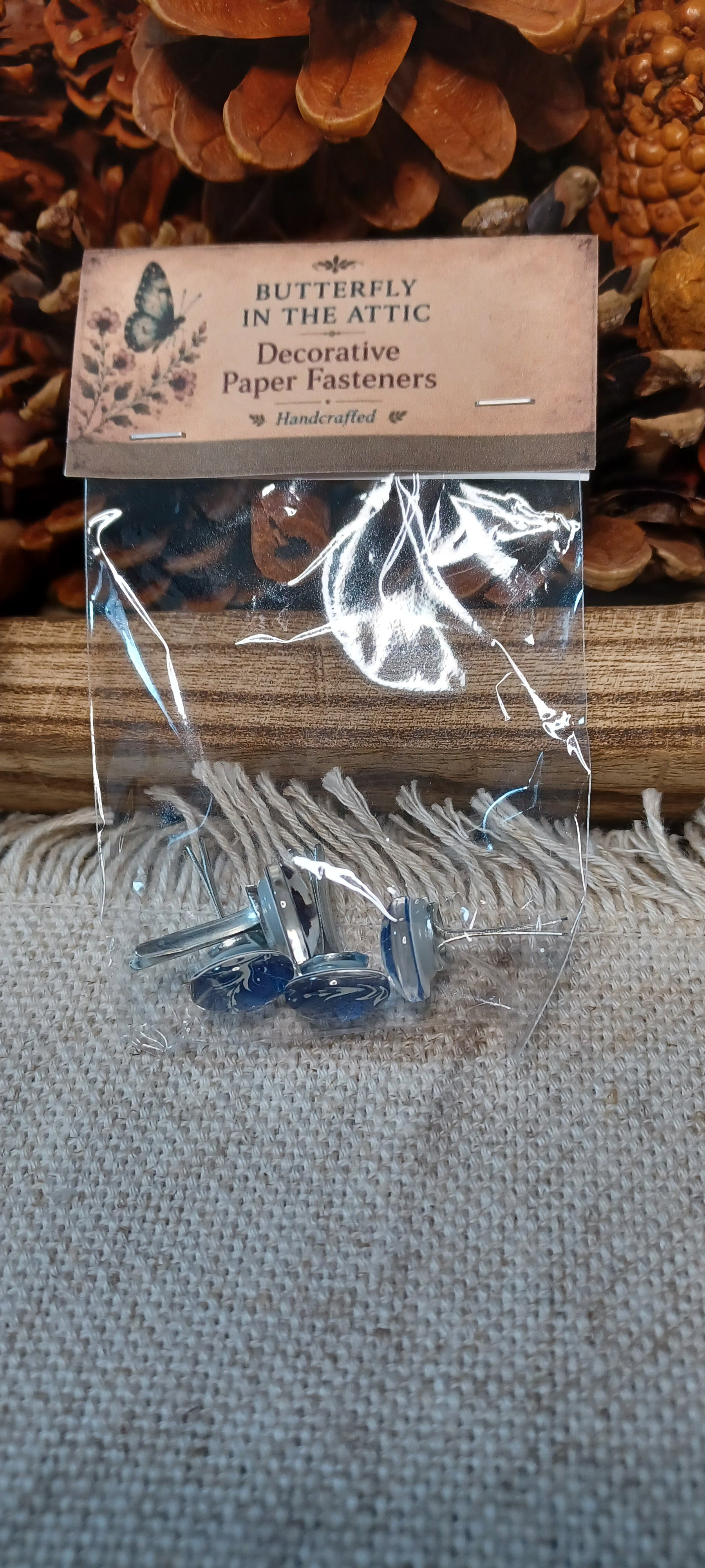 Packaged assorted blue and white cabochon decorative paper fasteners with patterns that vary by set