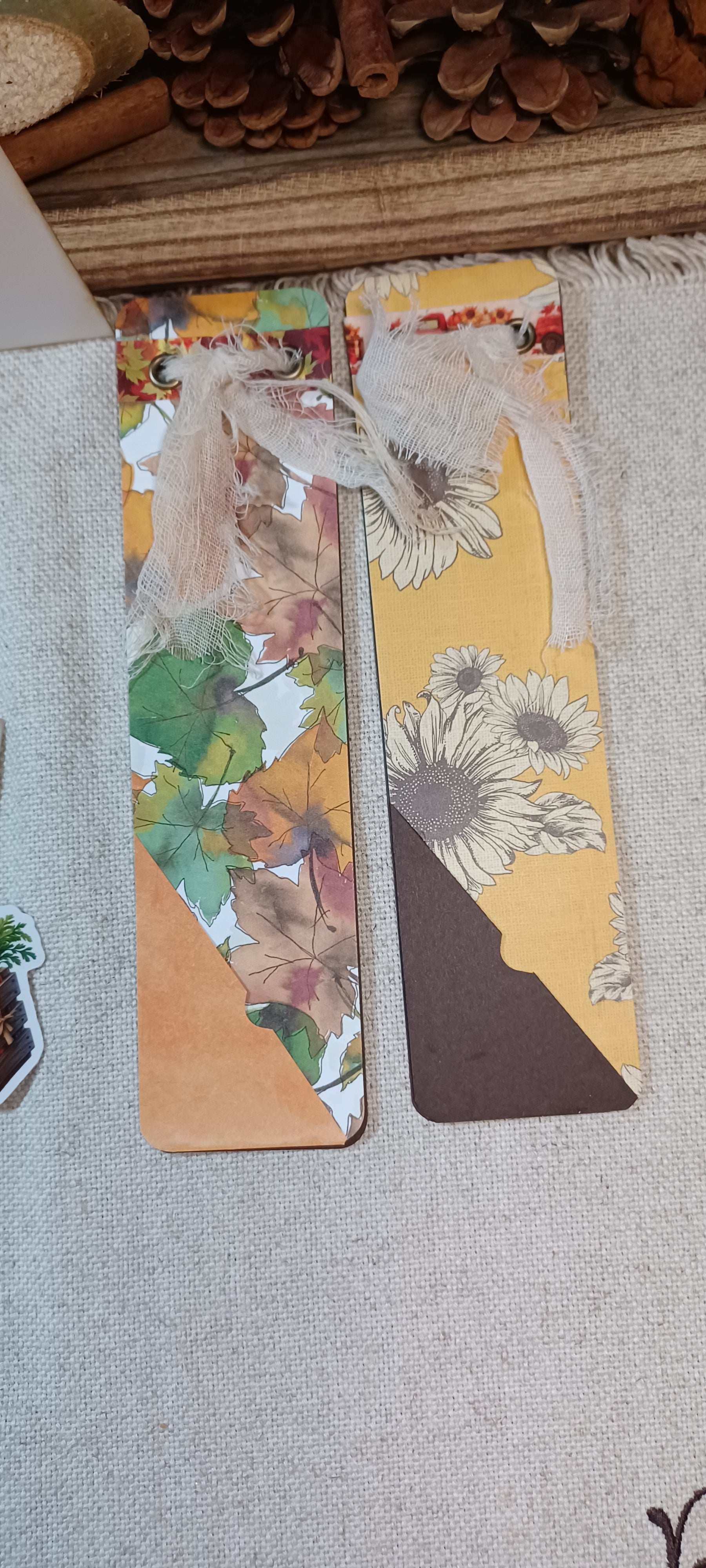 Two decorative paper bookmarks with floral and geometric patterns, laid flat on a light fabric surface.