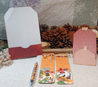 A styled flat-lay of autumn-themed stationery and decorative accessories on a textured cream fabric surface, featuring a white and red envelope, a pink patterned tag, a peach tag, a patterned pen, and two orange bookmarks with fall leaves and a dog illustration.