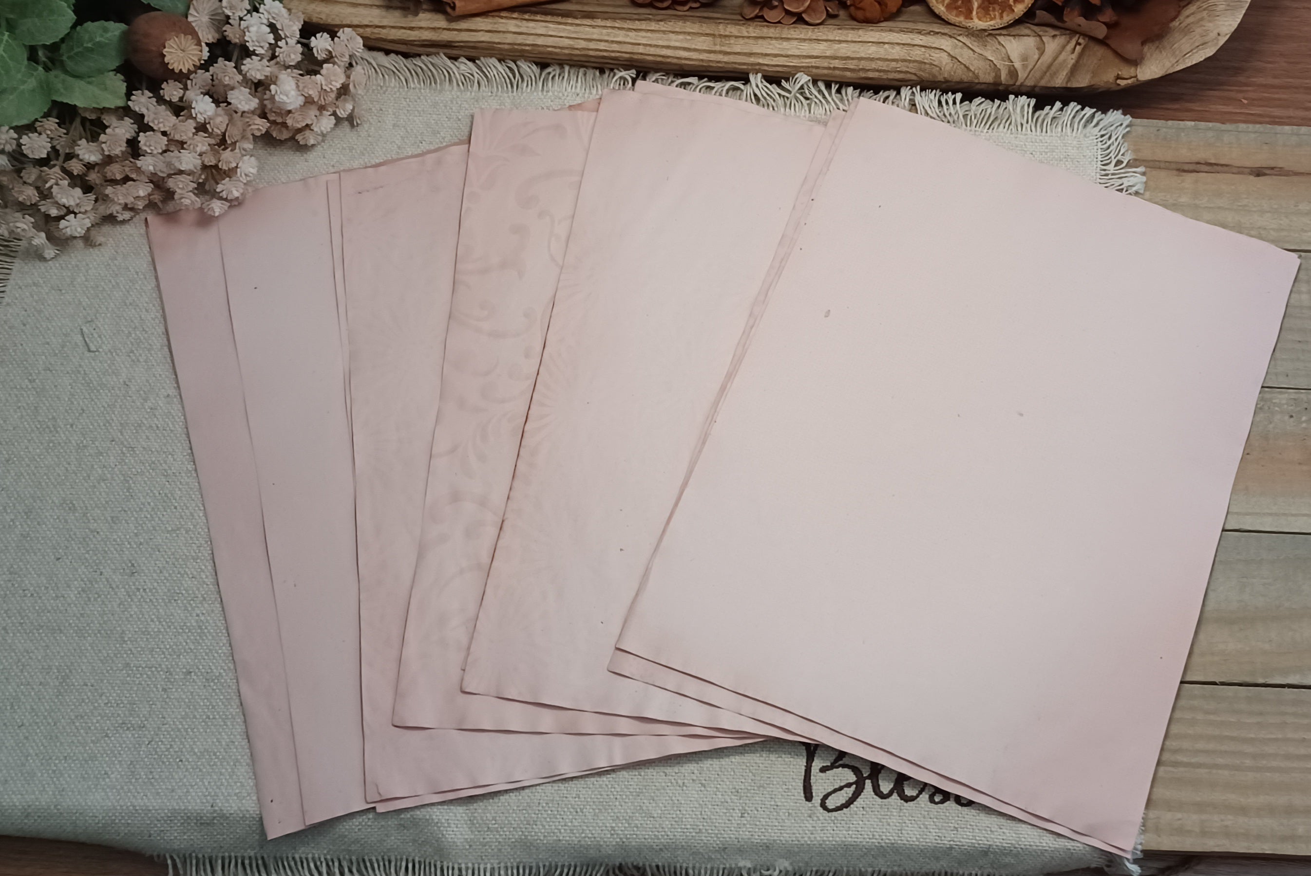Assorted 8.5 by 11 inch avocado-dyed papers with natural variations in soft pink tones