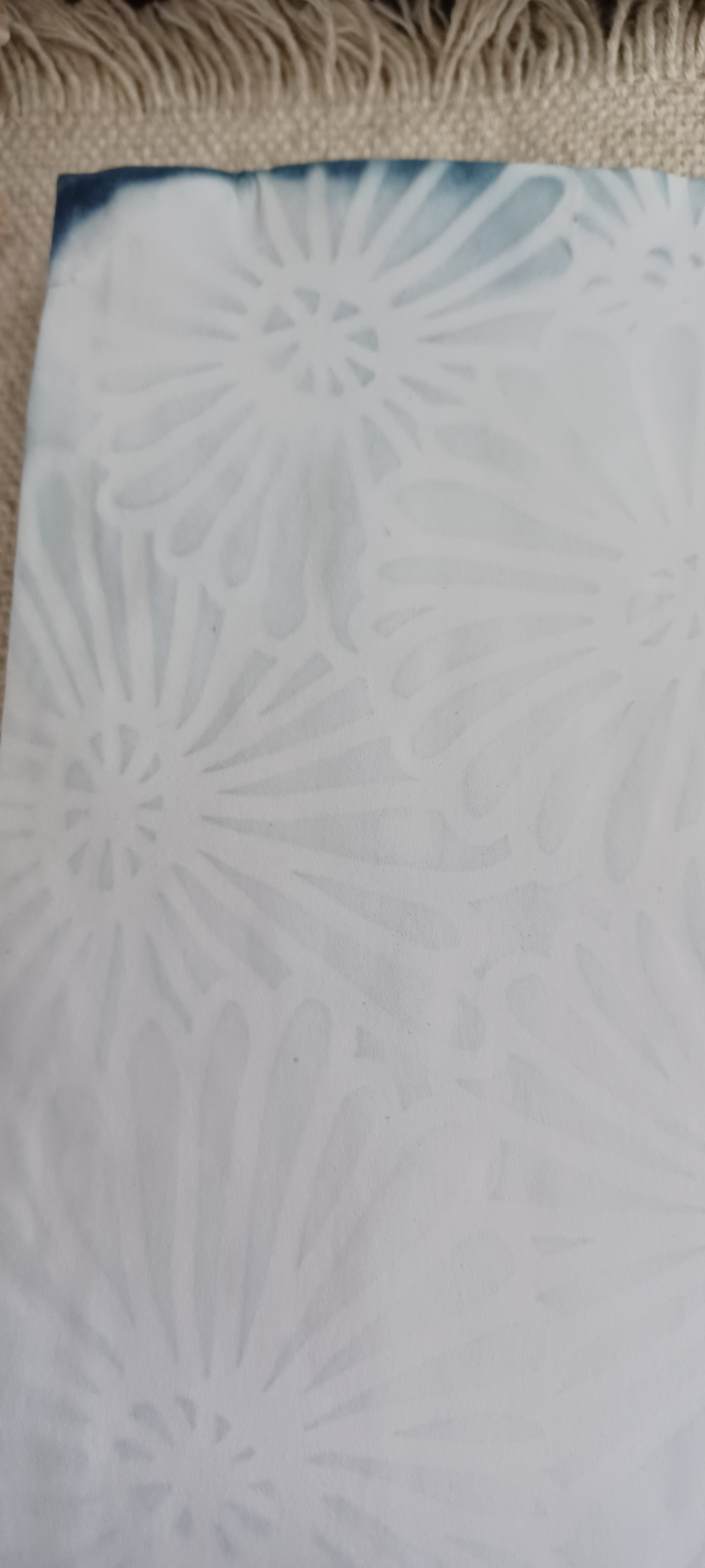 Close-up of sky blue red cabbage dyed paper featuring a decorative stencil pattern created during the hand dyeing process