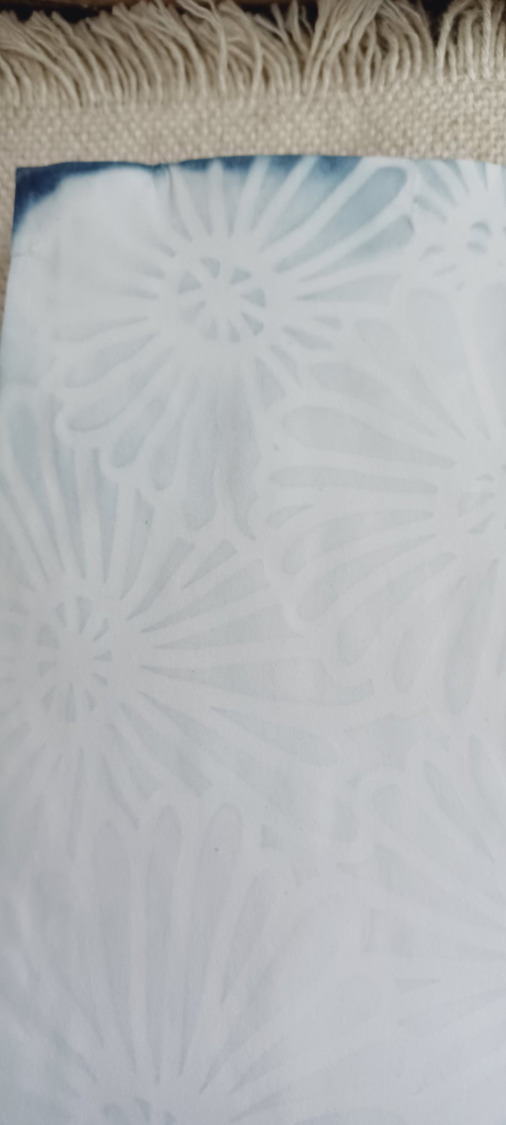 Detail of naturally dyed aqua blue paper showing stencil design, mottled color, and handmade variations in the surface