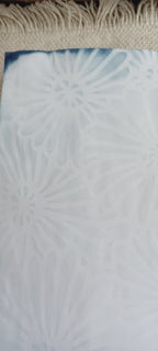 Detail of naturally dyed aqua blue paper showing stencil design, mottled color, and handmade variations in the surface