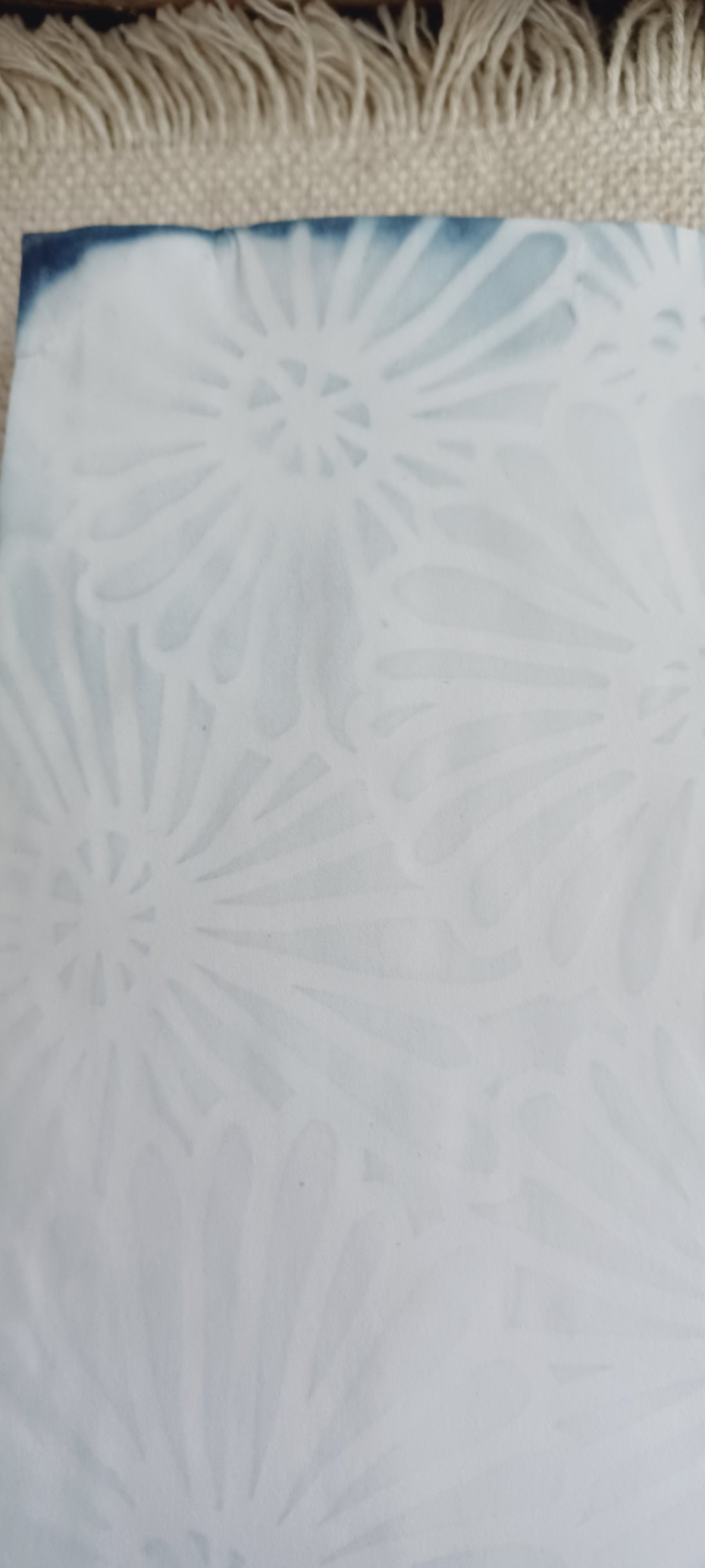 Detail of naturally dyed aqua blue paper showing stencil design, mottled color, and handmade variations in the surface