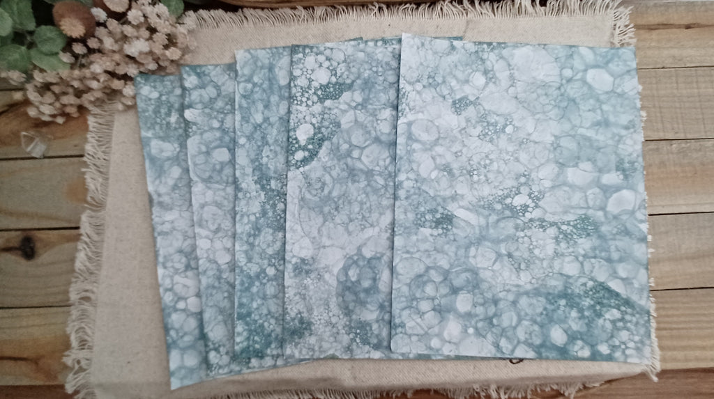 Five Green bubble-blown 8.5 x 11 paper sheets fanned out to show varied handmade bubble patterns
