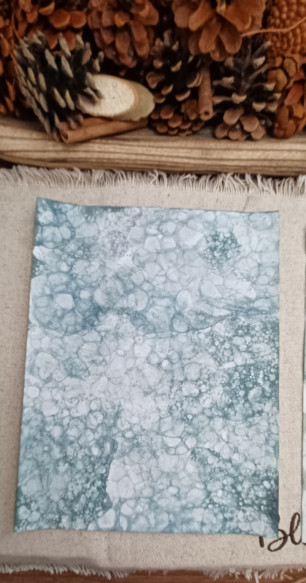Green hand-patterned paper with large bubble impressions surrounded by fine lacy networks of smaller bubbles