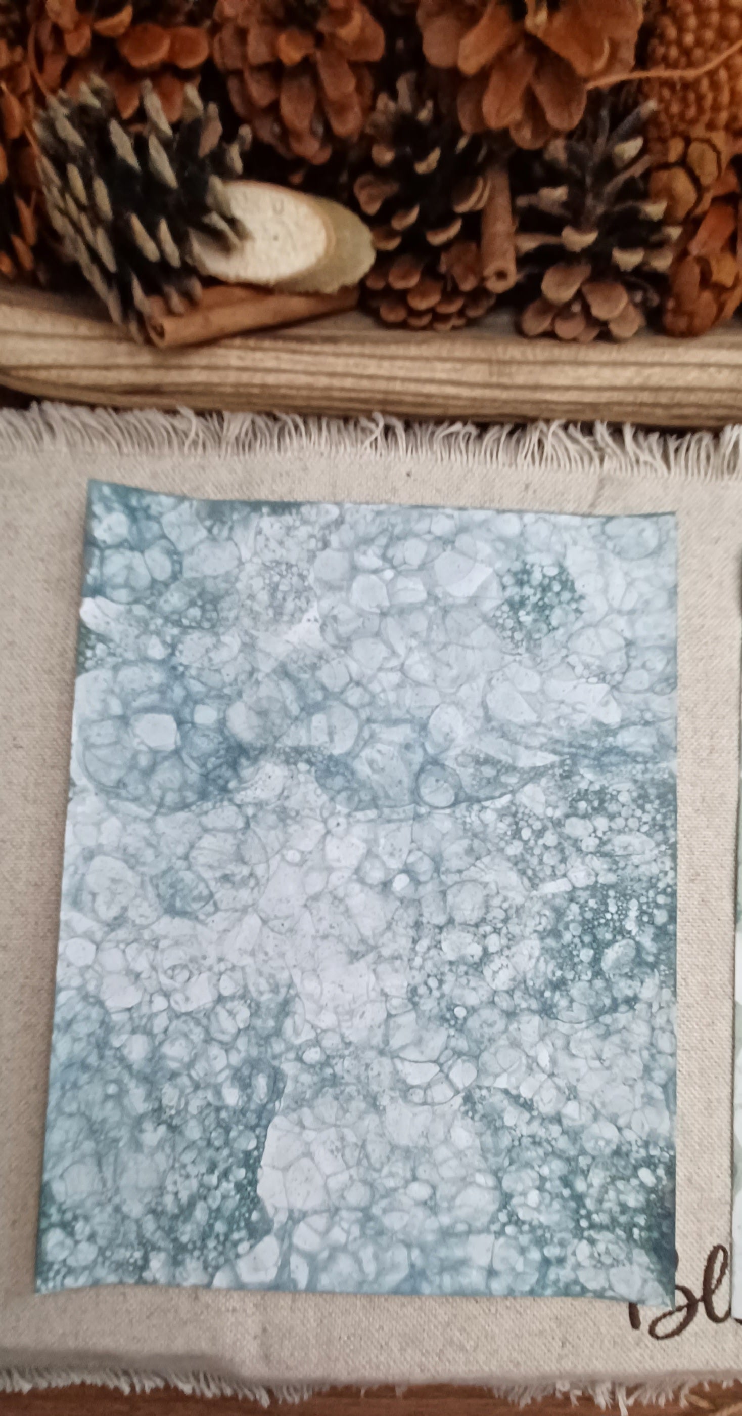Green hand-patterned paper with large bubble impressions surrounded by fine lacy networks of smaller bubbles