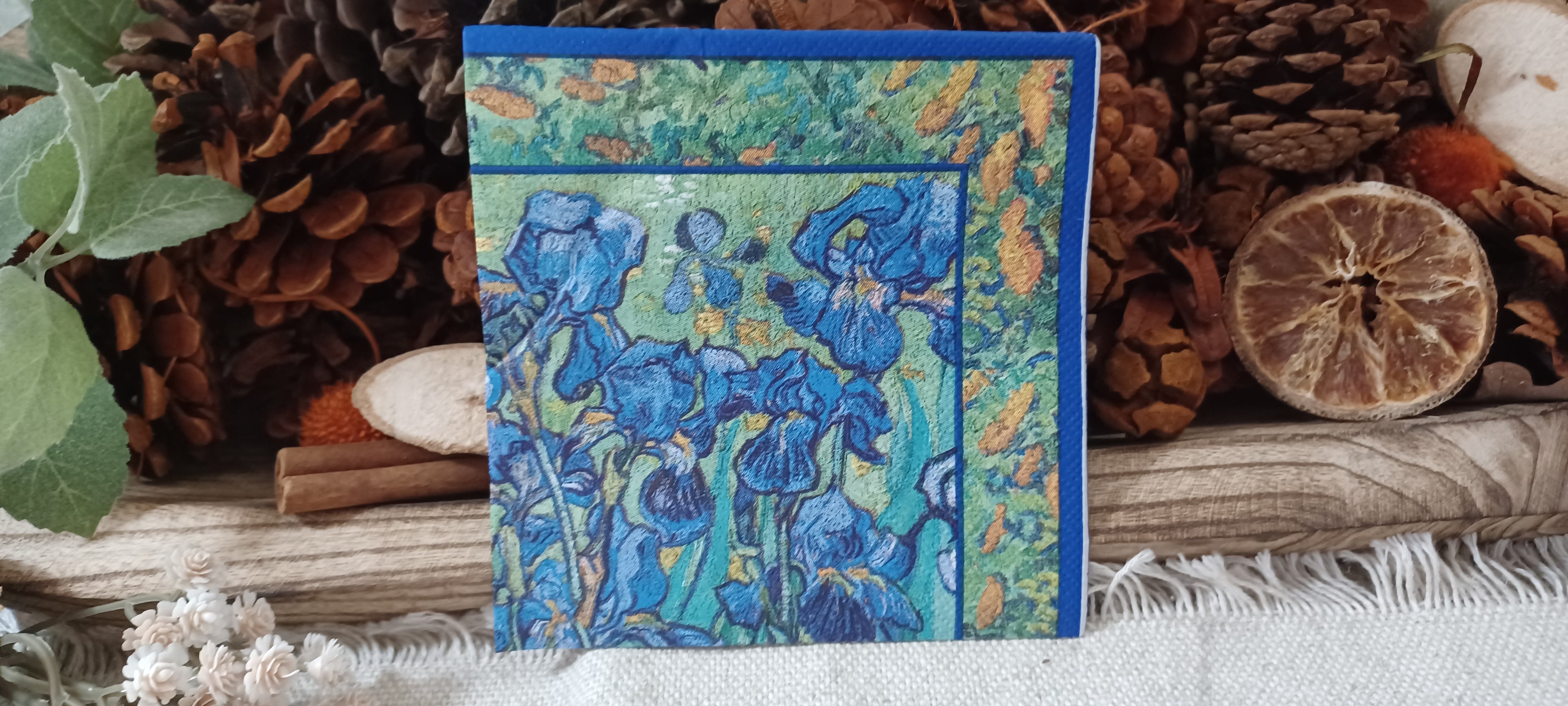 Blue iris floral cocktail napkin in cobalt, turquoise and green displayed with rustic botanical decor.