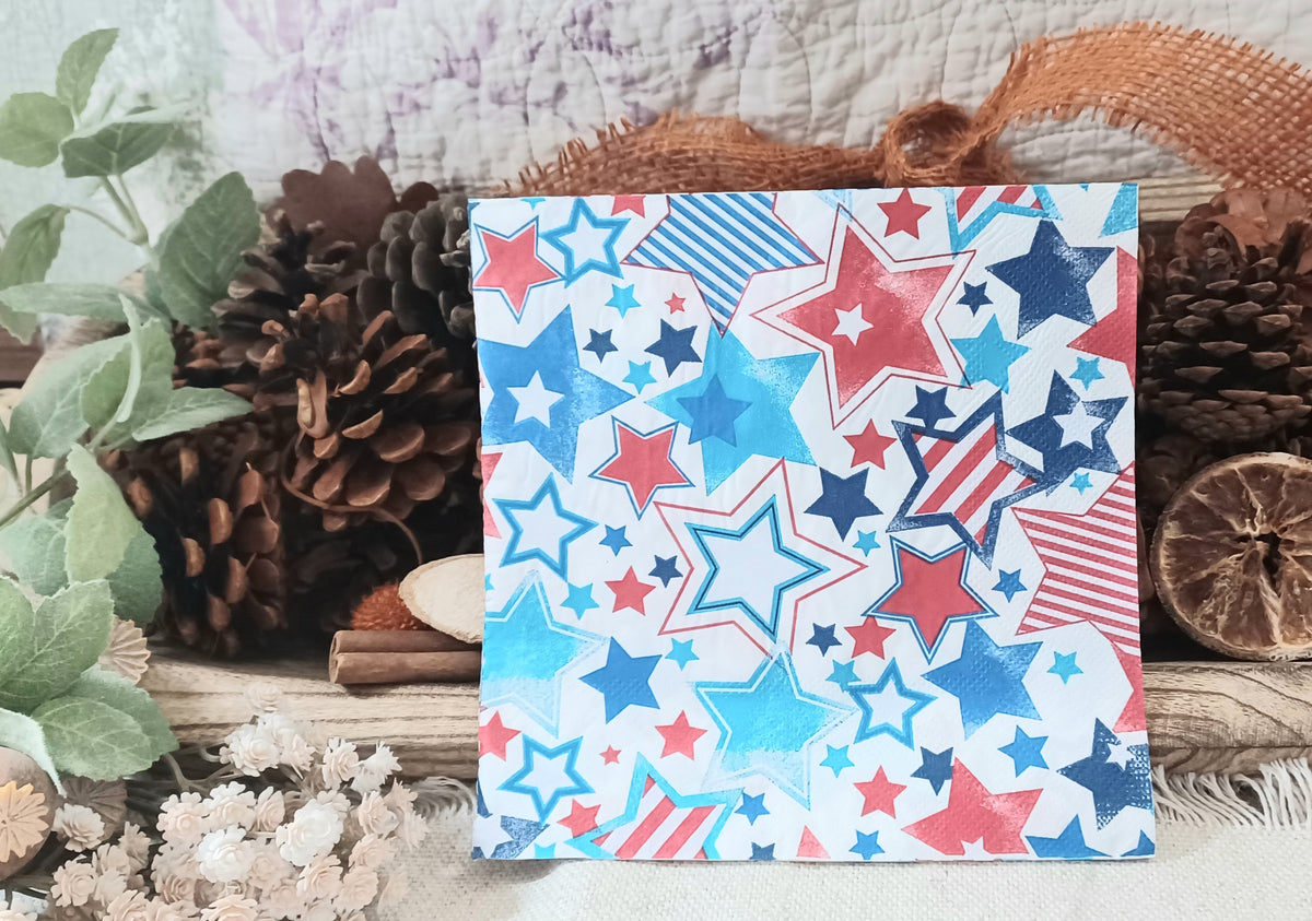 Single patriotic star paper napkin displayed with rustic pinecones, greenery and natural vintage-style décor.