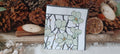 Sage green floral cocktail paper napkin with black botanical branches and golden accents for decoupage, collage and paper crafts.
