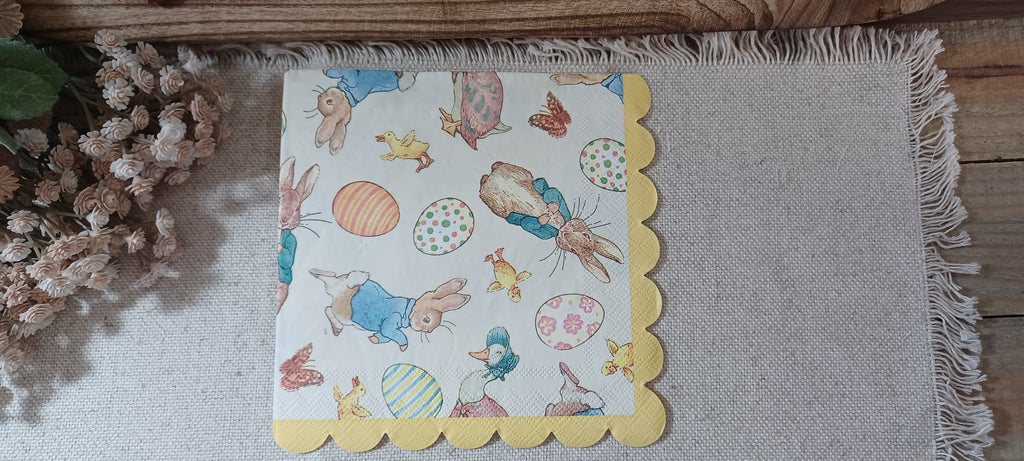 Luncheon-size Easter paper napkin featuring storybook rabbits, decorated eggs, chicks, ducks and a yellow scalloped border.