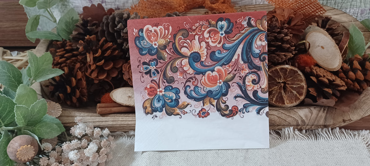 Reverse view of Norwegian folk art napkin with elaborate rosemaling floral scrolls in teal blue, coral, cream, and ochre.