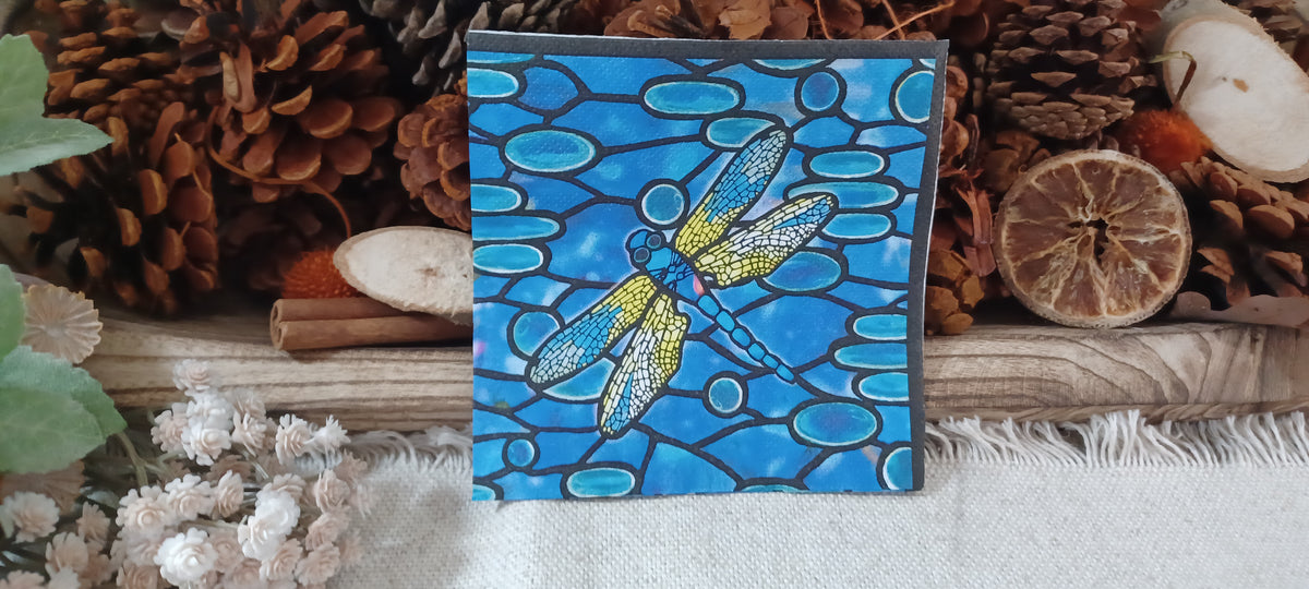 Stained glass dragonfly paper napkin displayed with rustic pinecones, dried orange, cinnamon and natural botanical accents.