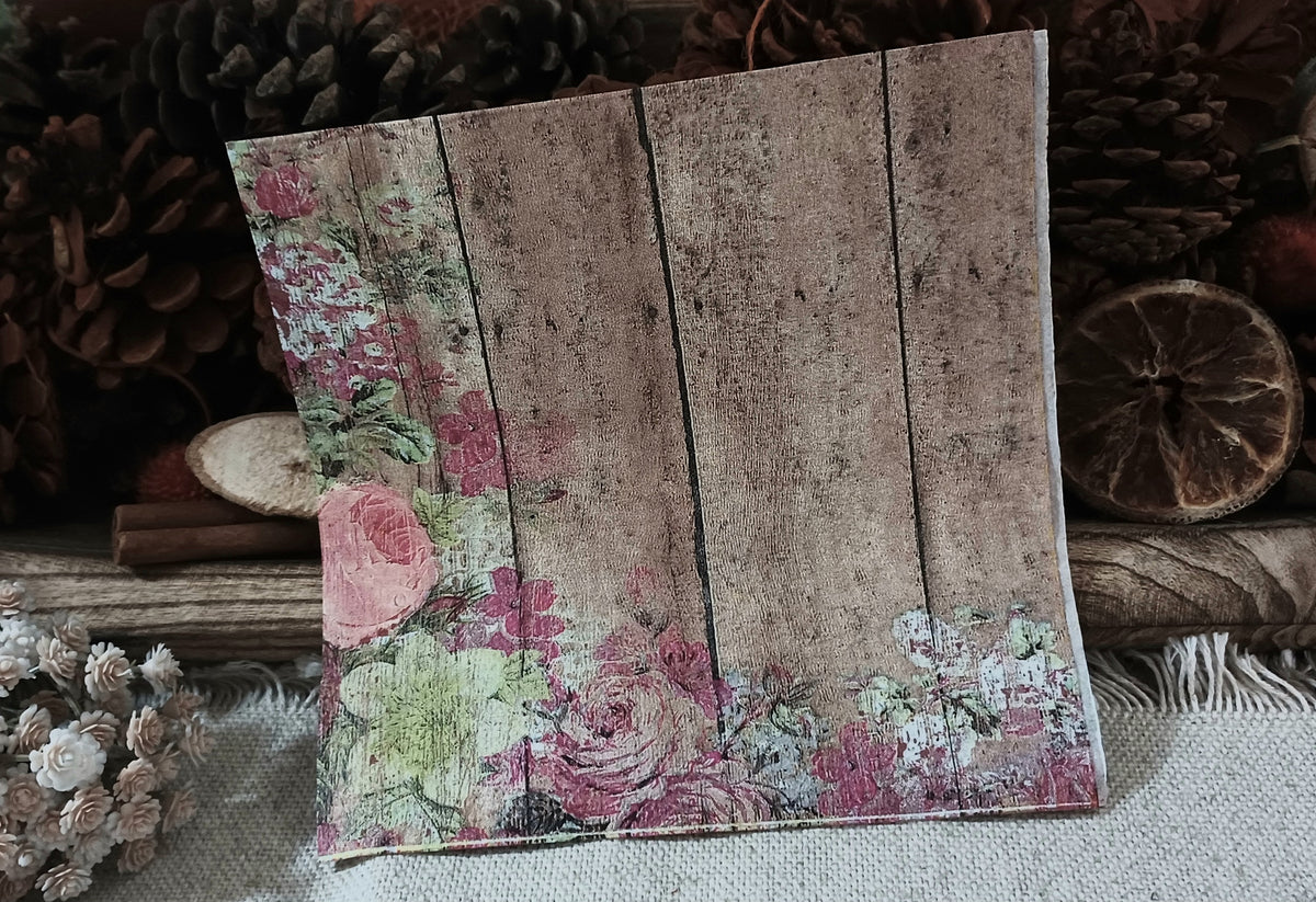 Vintage floral decoupage napkin featuring weathered brown boards with faded roses and botanical details.