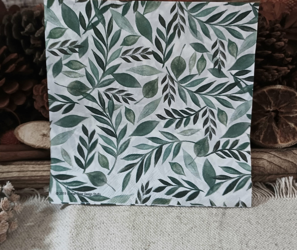 Green leaf luncheon napkin displayed upright, showing the watercolor botanical pattern on a white background.
