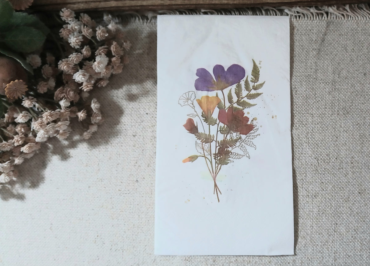 Large white guest napkin with a delicate pressed wildflower bouquet in purple, rust, golden yellow and muted green.