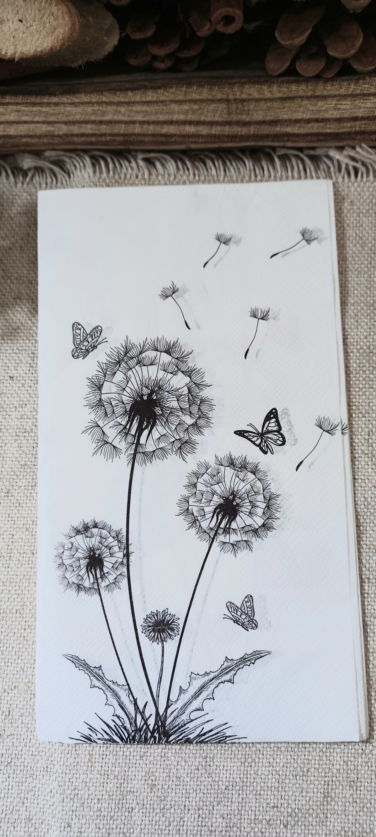 Decorative dandelion and butterfly guest napkin with detailed black botanical illustrations on a white background.