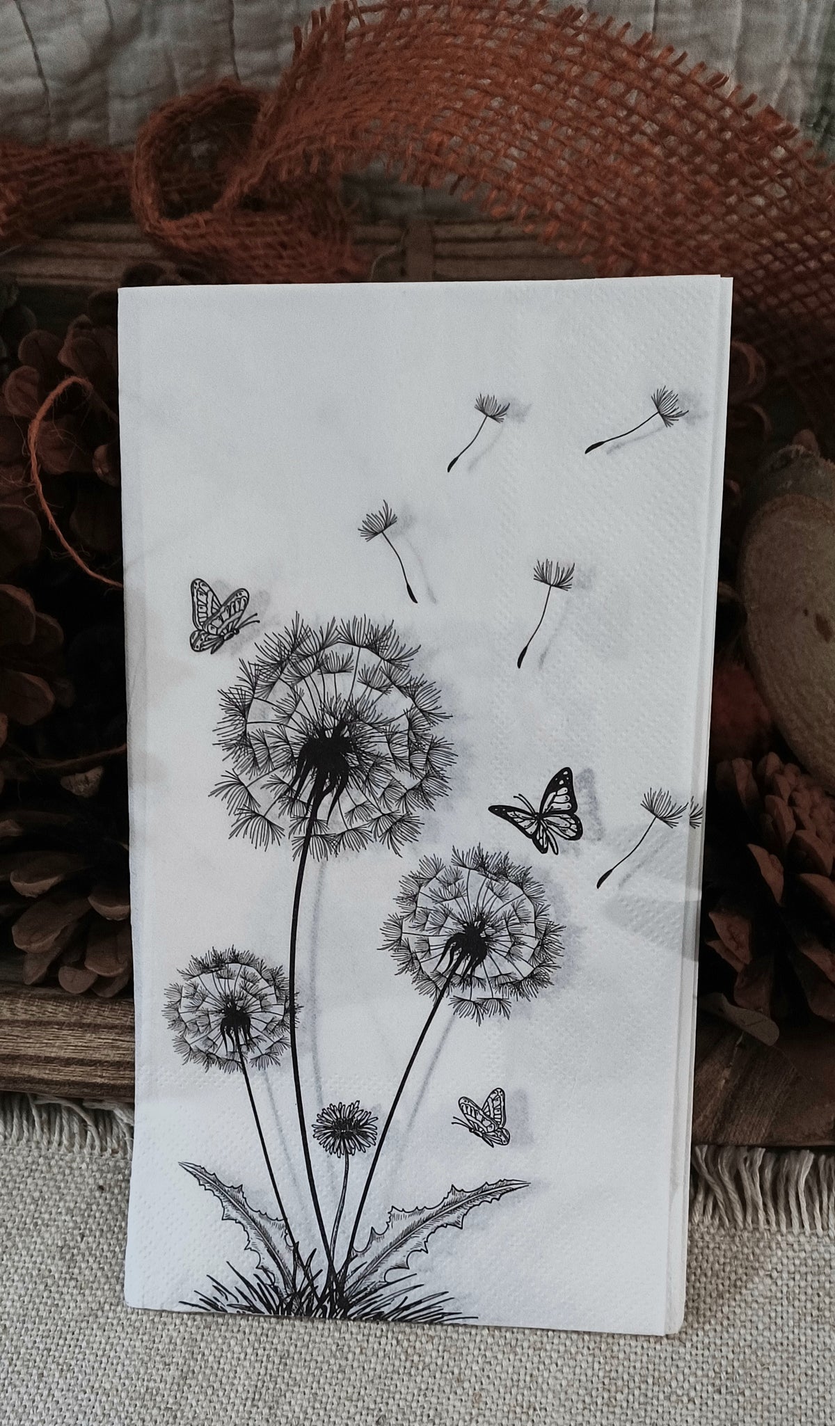 Large paper guest napkin with black dandelion flowers, drifting seeds and butterflies for decoupage and paper crafts.