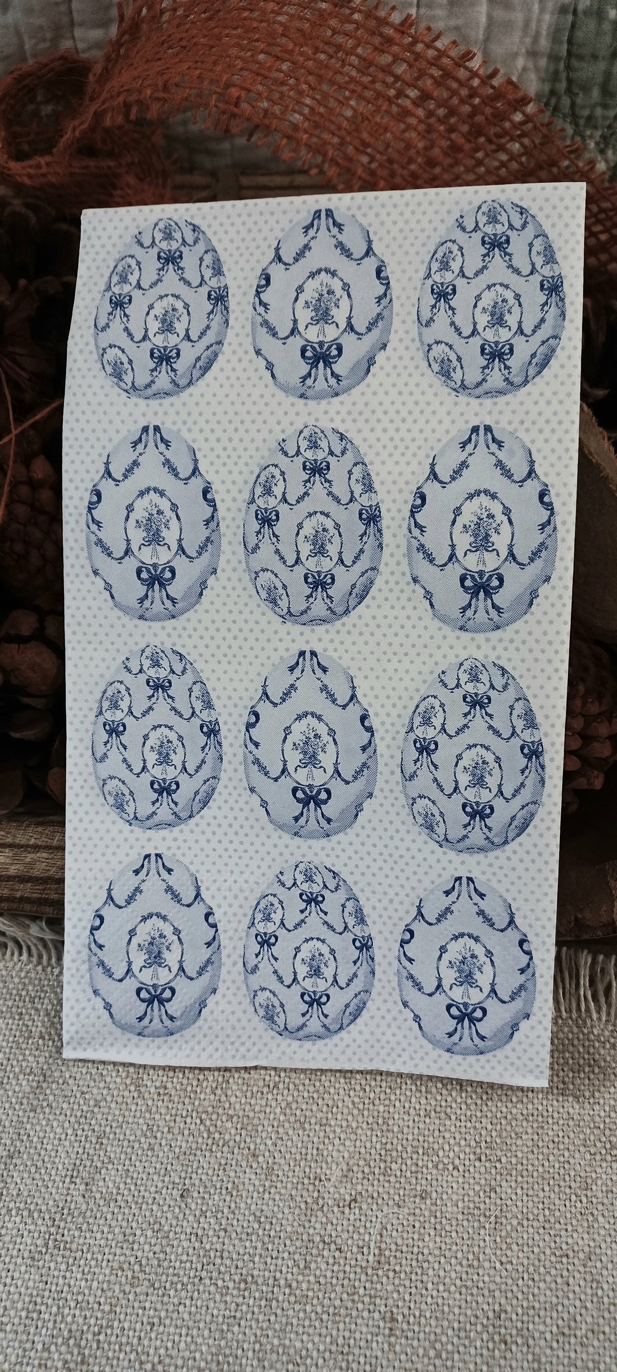 Close view of a blue and white decorative guest napkin with vintage floral oval motifs and bow details.