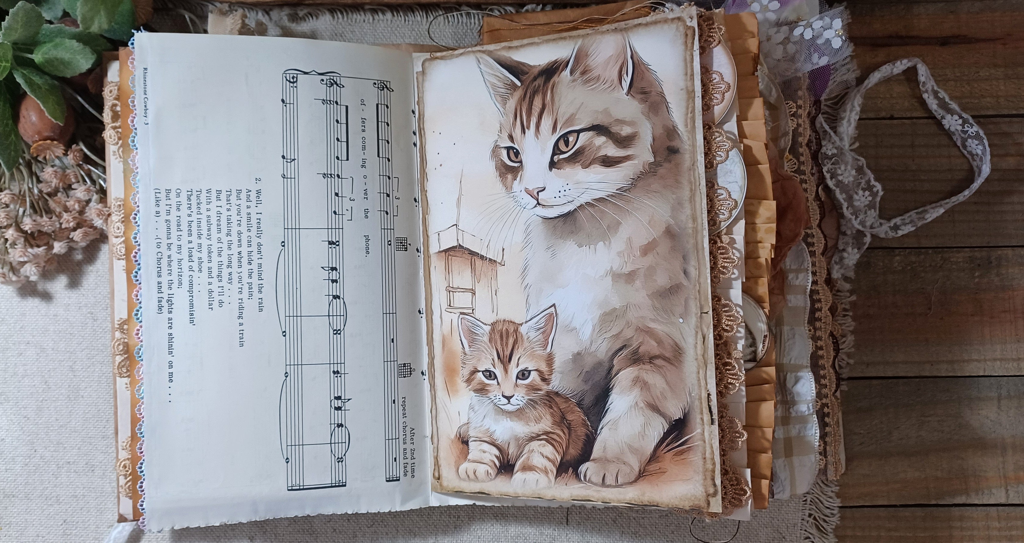 Open cat junk journal spread surrounded by layered lace, fabric trims and ruffled page edges.