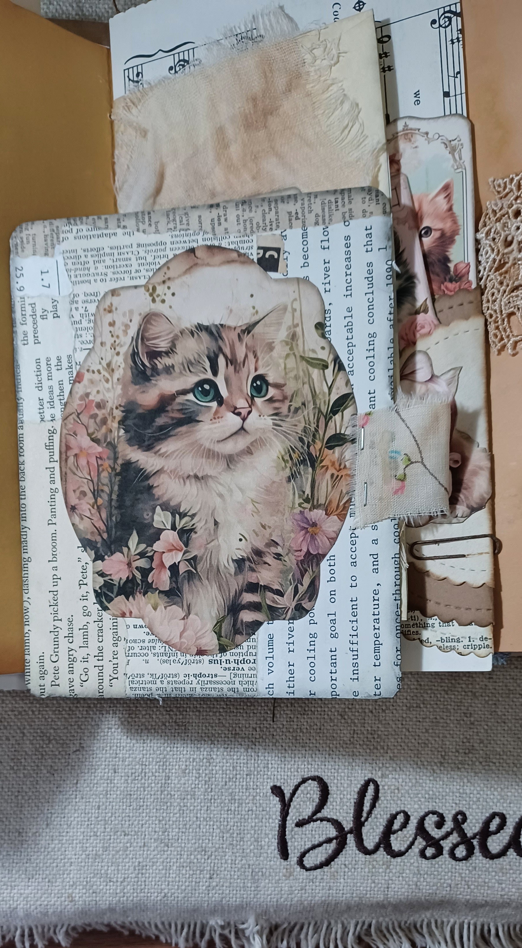 Layered vintage cat embellishment inside handmade lace and ruffle junk journal.