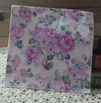 Vintage-style mauve and lilac rose luncheon napkin displayed with old books and crochet lace.