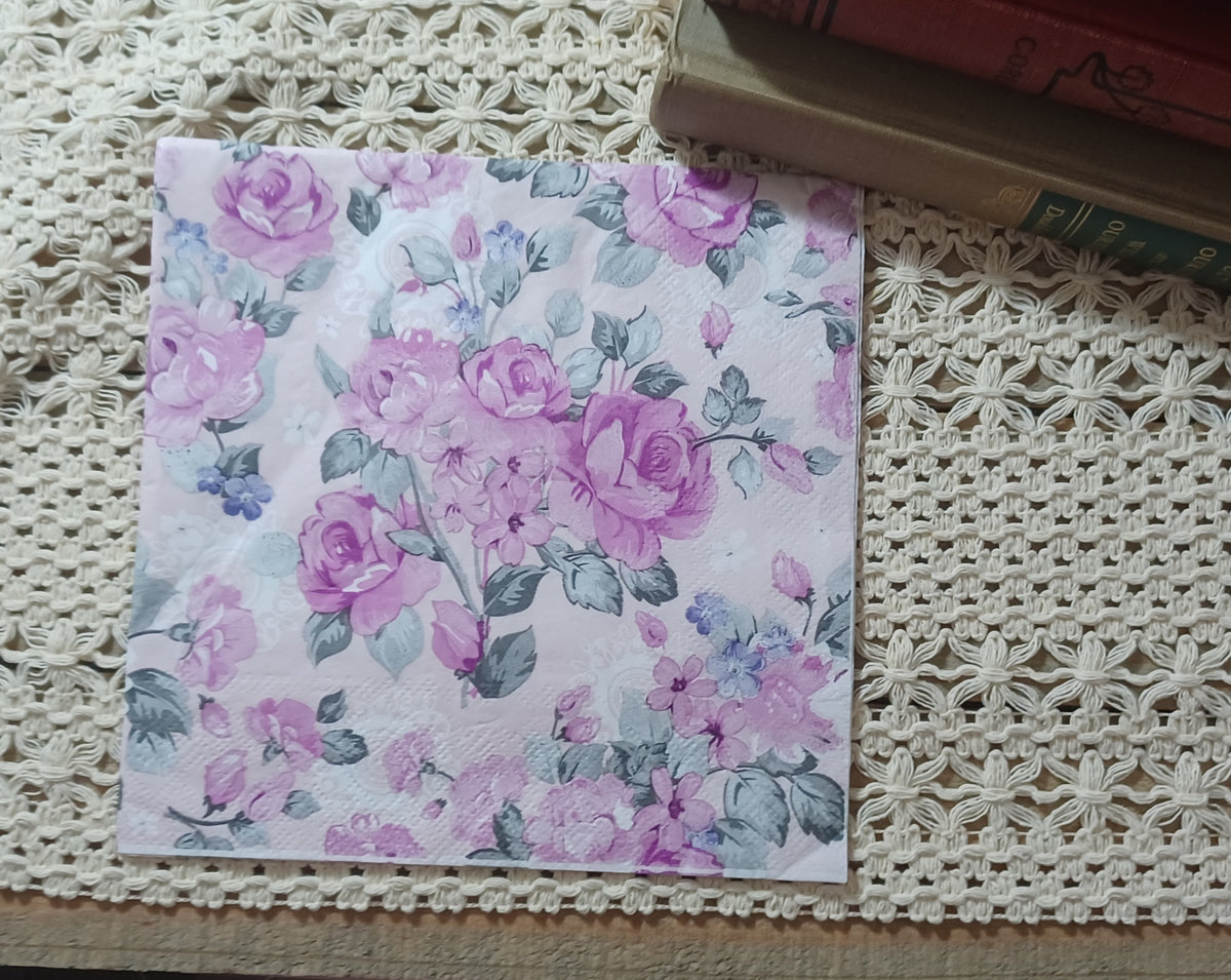 Full luncheon decoupage napkin with mauve roses, dusty blue flowers, and gray-green leaves in a vintage chintz pattern.