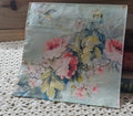 Watercolor-style pink floral luncheon napkin with pale aqua background displayed beside vintage books.