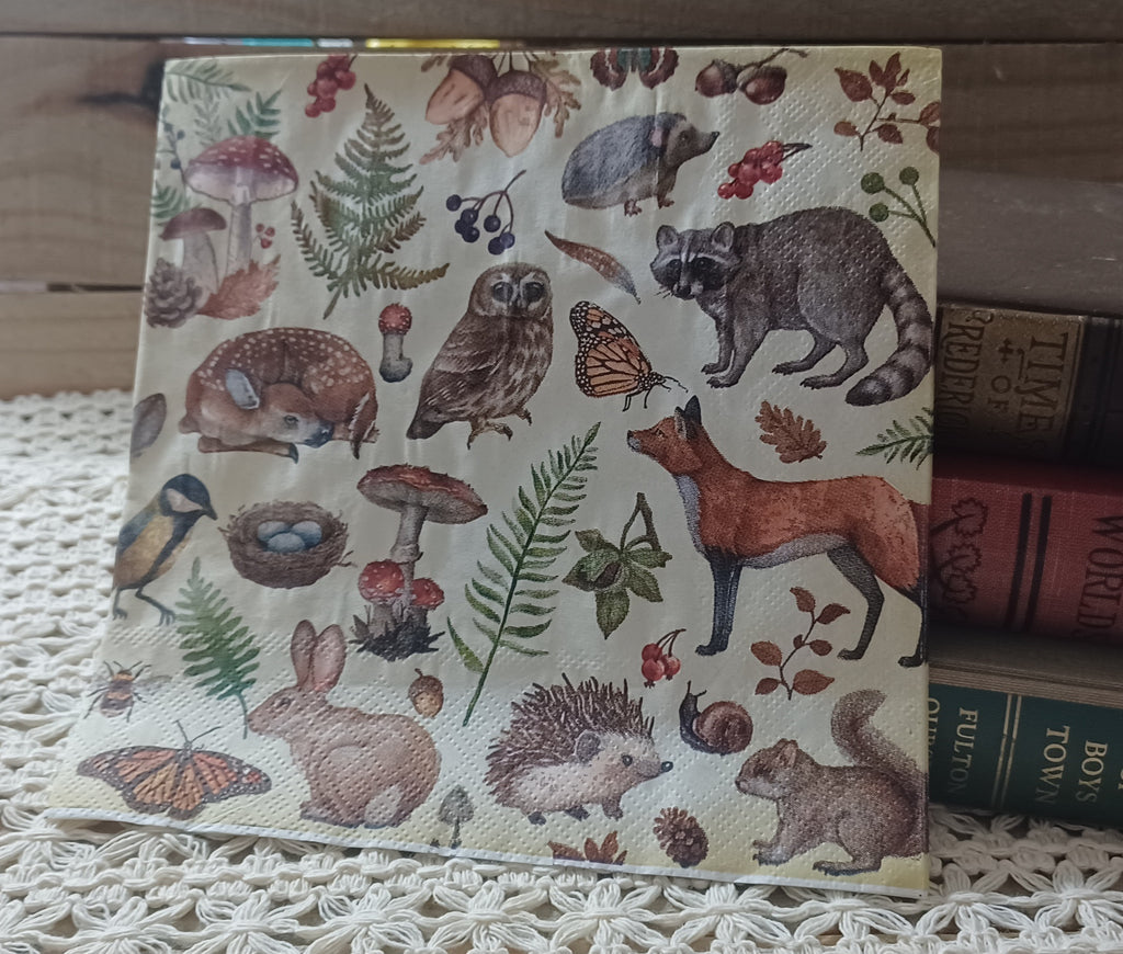 Woodland animal luncheon napkin with fox, owl, raccoon, rabbit, hedgehog, squirrel, mushrooms, ferns, and butterflies.