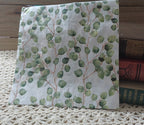 Watercolor eucalyptus leaf luncheon napkin with soft green foliage and slender brown stems on white.