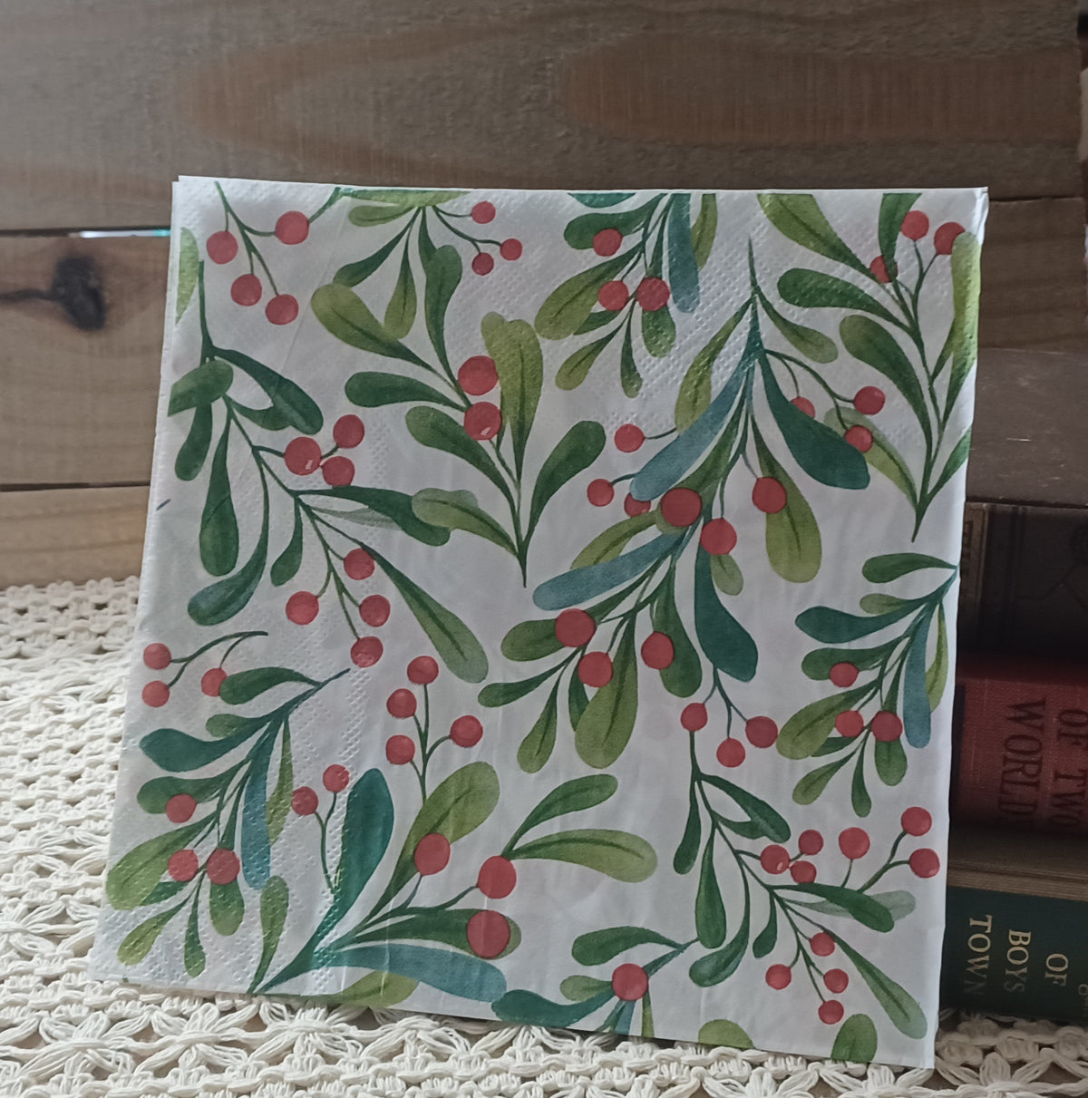Full luncheon paper napkin with watercolor green leafy branches and red berries on a white background.