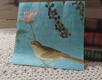 Turquoise blue luncheon paper napkin featuring a vintage-style garden bird beneath a pale pink flower and dark berry branches.