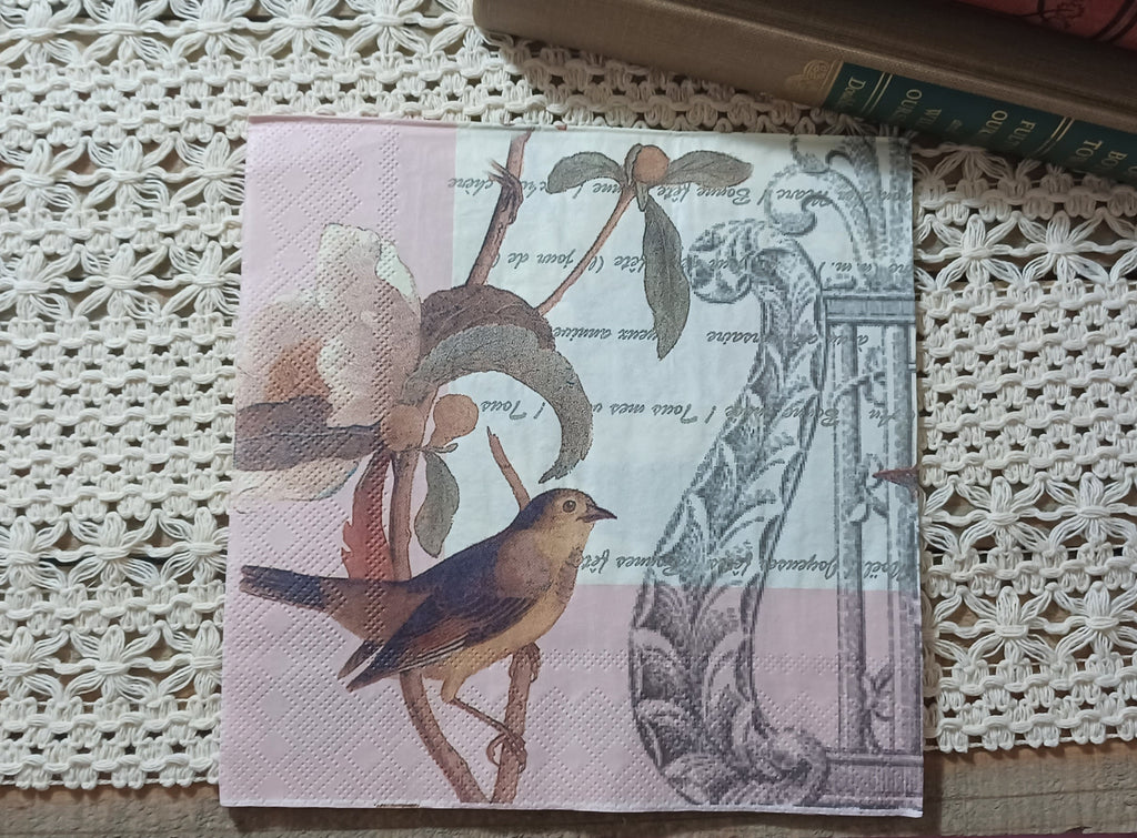 Blush pink vintage-style paper luncheon napkin featuring a small songbird, faded flower, antique handwriting and architectural illustration.