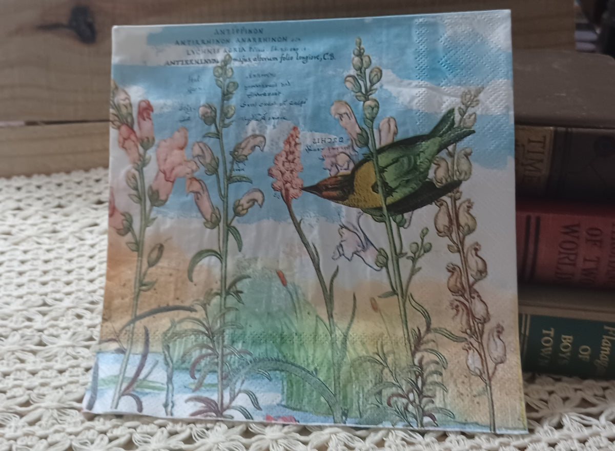Vintage-style paper napkin featuring a green and yellow bird flying among tall pink wildflowers with a soft blue and cream botanical background.