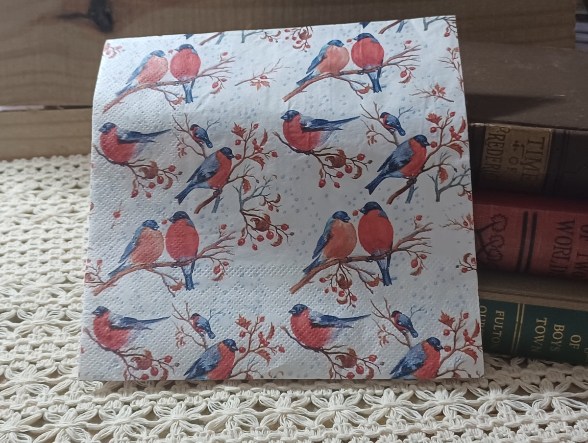 Single winter bird decoupage napkin with red and blue birds, pairs of birds perched together, red berry branches and a softly dotted snowy background.
