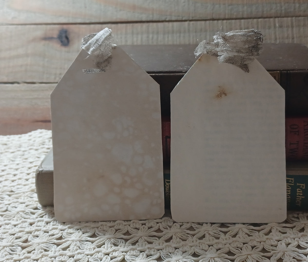 Close view of handmade grungy owl tags with raised white crackle, violet paint and aged book pages