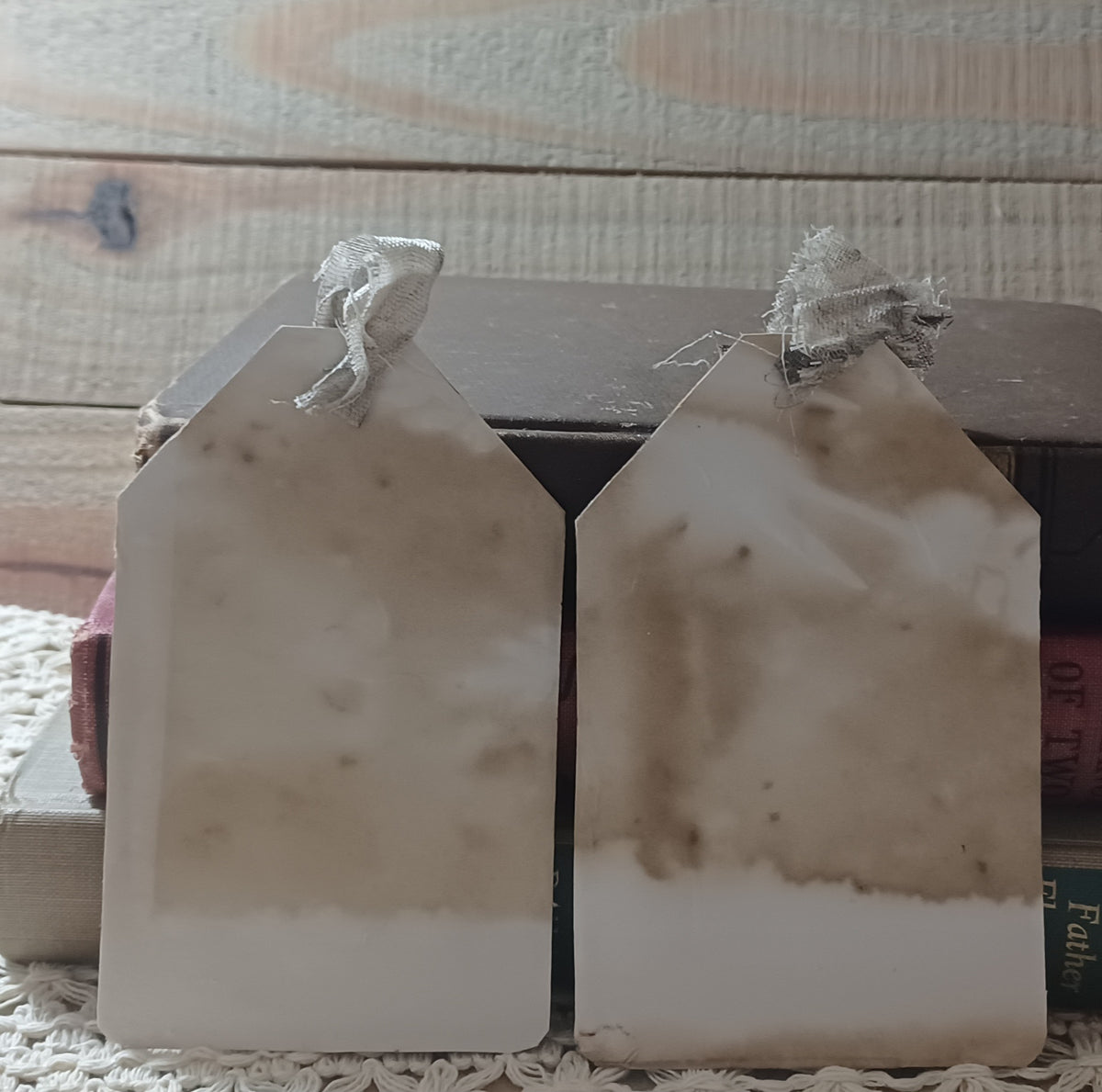 Close view of handmade grungy owl tags with charcoal paint, faded mauve and weathered vintage paper