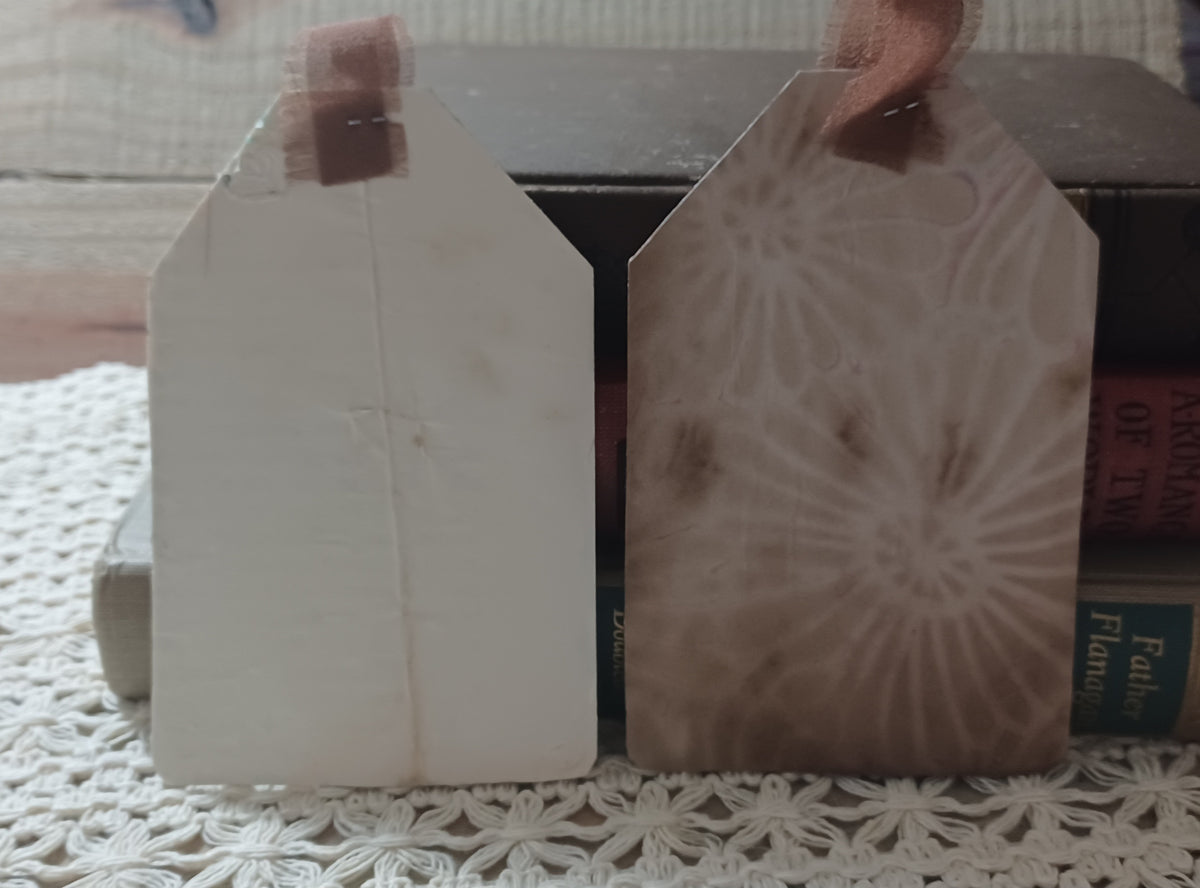 Close view of handmade grungy owl tags with raised brick and stone-like texture over aged book pages