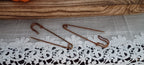 Two large industrial-style clothing pins with an uneven genuine rust finish displayed on a lace-covered surface
