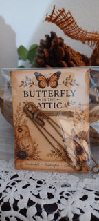 Two genuinely rusted 3½-inch safety pins packaged on a Butterfly In The Attic backing card in a clear protective sleeve