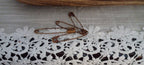 Four 2-inch metal safety pins with varied reddish-brown genuine rust finishes displayed on a lace-covered surface