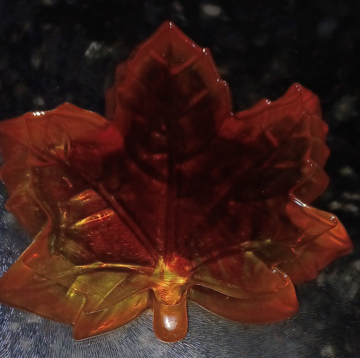 back side of handmade translucent resin maple leaf trinket dish in orange, red and golden autumn colors