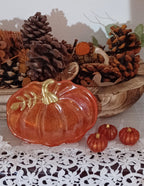 Handmade orange resin pumpkin trinket dish with gold stem and leaf detailing, accompanied by three matching miniature resin pumpkins.