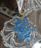 Handmade translucent icy-blue resin snowflake Christmas ornament with intricate openwork details and attached gold hanging string.