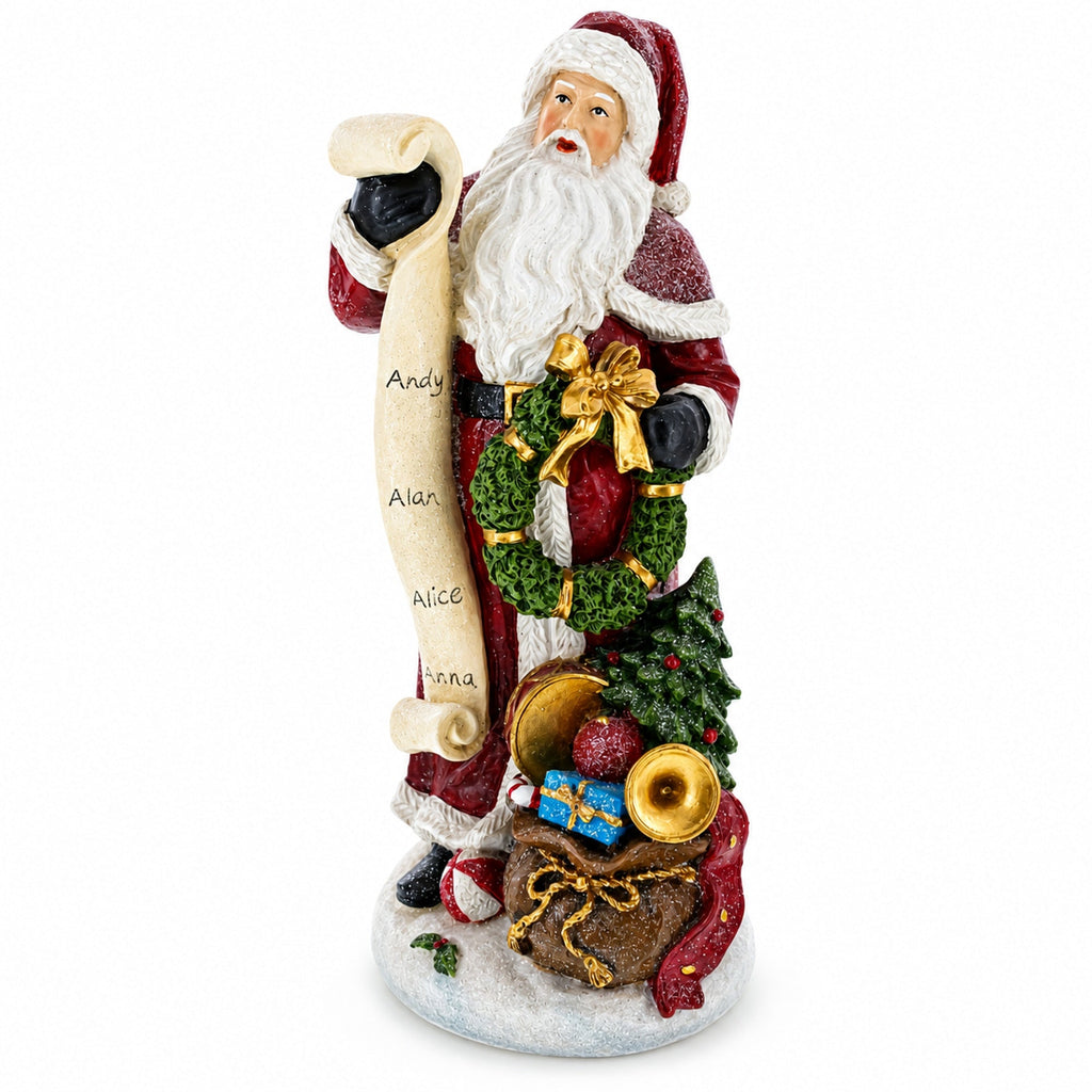 A Santa Claus figurine holding a scroll with names, decorated with a green wreath, gold bow, Christmas tree, ornaments, and gifts at the base, shown on a plain white background.
