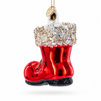 A red Christmas ornament shaped like a boot, with a white cuff covered in clear rhinestones, a black glittery sole, and a gold hanging loop at the top, shown on a plain white background.