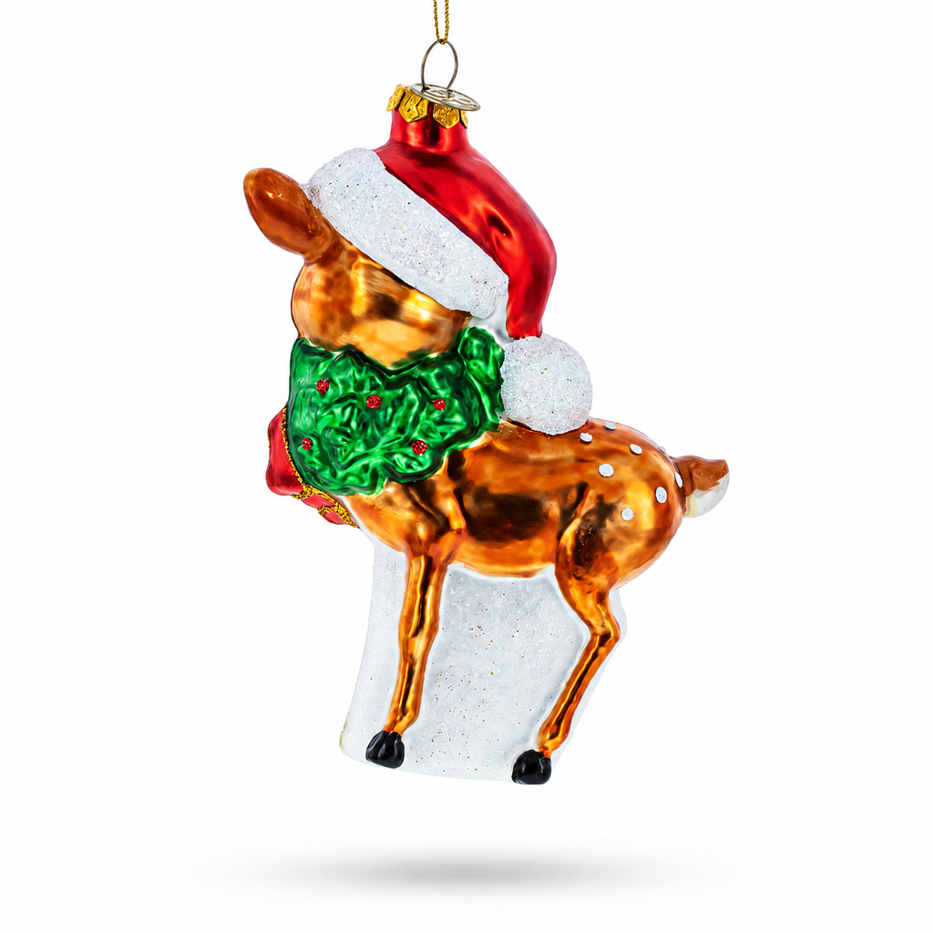 A festive Christmas ornament shaped like a deer wearing a red Santa hat with a white pom-pom and a green wreath with red berries, shown on a clean white background.