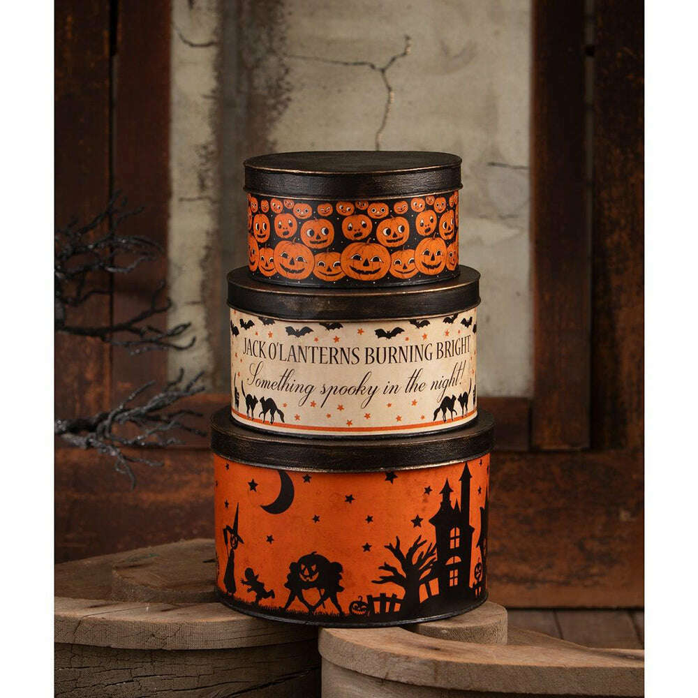Halloween nesting tins displayed on a rustic wooden shelf, showing their antiqued finishes and decorative printed-paper designs.