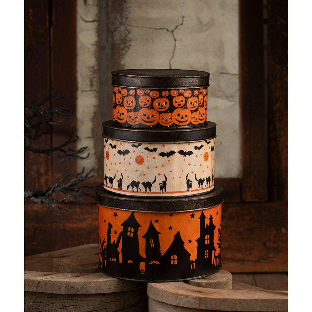 Three vintage-inspired Halloween tins stacked together against a dark backdrop.